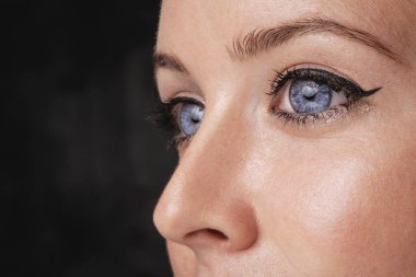 Mavi gözlü, siyah göz kalemi ve rimel sürmüş bir kadın resmi. İzole edilmiş arkaplan.