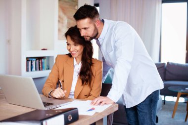 Gülümseyen iş adamları yeni projede çalışırken dizüstü bilgisayar kullanıyorlar. 