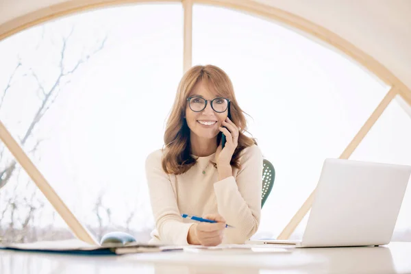 Szczęśliwa Bizneswoman Siedzi Komputerem Mając Telefon Podczas Pracy — Zdjęcie stockowe