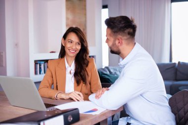 Gülümseyen iş adamları yeni projede çalışırken dizüstü bilgisayar kullanıyorlar. 