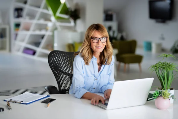 Glimlachende Zakenvrouw Werkt Aan Haar Laptop Terwijl Aan Het Bureau — Stockfoto