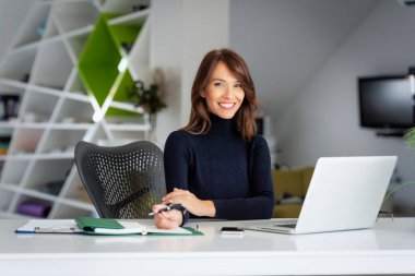 Kendine güvenen orta yaşlı iş kadını dizüstü bilgisayarının arkasında oturuyor ve yeni bir proje üzerinde çalışıyor. Merkez Ofis.