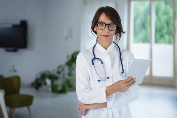 病院の廊下に立っている間 彼女の患者チャートをデジタルタブレットで保持している女性医師の肖像画 — ストック写真