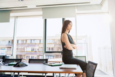 Attractive businesswoman looking thoughtfully while sitting in the office and looking out the window. 
