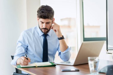 Cropped shot of confident businessman sitting at desk behind his laptop and looking thoughtfully while working in the office.
