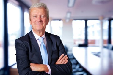 Shot of executive senior businessman wearing suit and tie while standing at the meeting room.