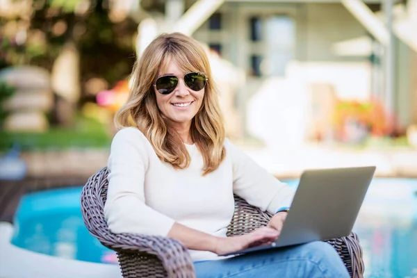 Attractive Middle Aged Woman Using Laptop While Sitting Backyard Home — стоковое фото