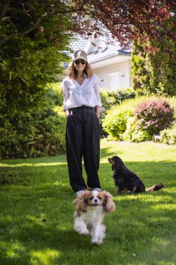 Smiling woman standing at the backyard with her cute puppies. 