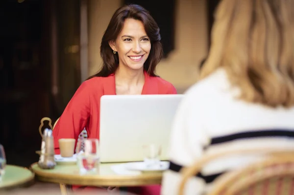 Усміхнена Жінка Сидить Відкритому Повітрі Терасі Кафе Своїм Ноутбуком Розмовляє — стокове фото