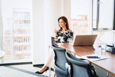 Shot of a mature businesswoman drinking a coffee while sitting at office desk and relaxing.