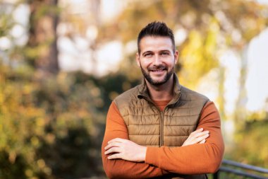 Portrait of  handsome man wearing sweater and west while standing outside in autumn weather. 