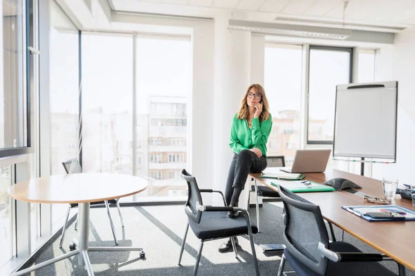 Çekici Bir Kadınının Modern Bir Ofiste Oturup Telefonda Konuşması — Stok fotoğraf
