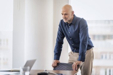 Ofiste masa başında duran bir iş adamı. Profesyonel erkek tişört giyiyor..