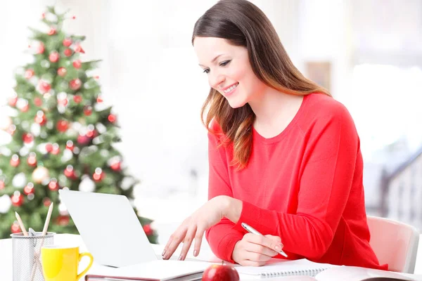 一个有魅力的女人用笔记本电脑在家里做一些文书工作的肖像 背景是一棵圣诞树 总部办公室 — 图库照片