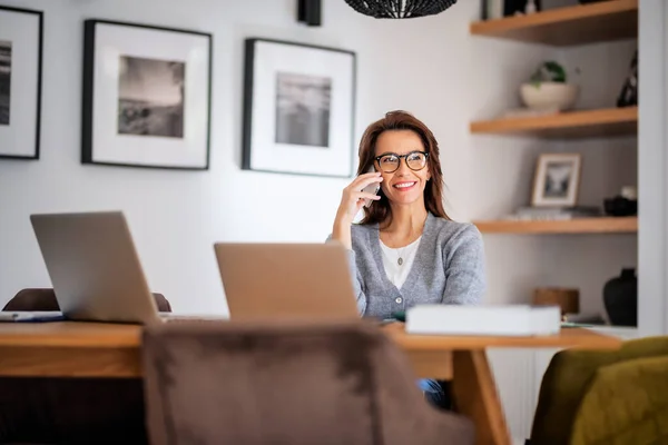 집에서 일하는 안경을 평상복을 매력적 노트북을 사용하고 전화를 비지니스 여성입니다 — 스톡 사진