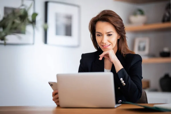 Tiro Uma Mulher Negócios Atraente Usando Laptop Smartphone Enquanto Trabalhava — Fotografia de Stock