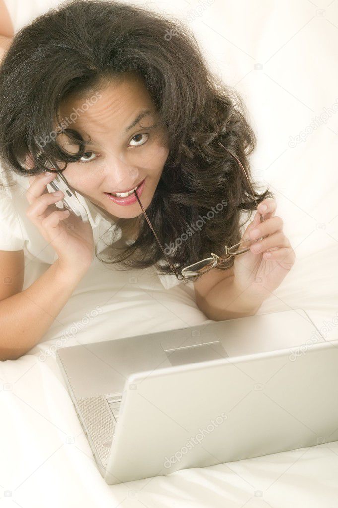 woman in bed with laptop and phone