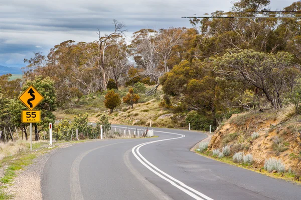 Camino sinuoso con advertencia de velocidad en Tasmania —  Fotos de Stock