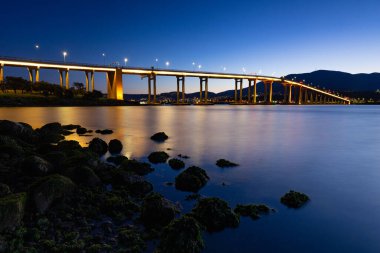 Günbatımında ikonik Tasman Köprüsü açık bir bahar akşamı Hobart, Tazmanya, Avustralya 'daki Derwent Nehri' ni geçer. Clarence 'ın kıyılarından çekildi.
