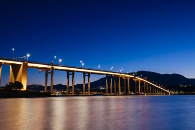 Günbatımında ikonik Tasman Köprüsü açık bir bahar akşamı Hobart, Tazmanya, Avustralya 'daki Derwent Nehri' ni geçer. Clarence 'ın kıyılarından çekildi.