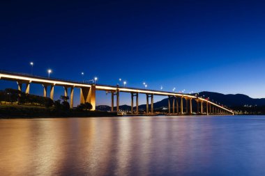 Günbatımında ikonik Tasman Köprüsü açık bir bahar akşamı Hobart, Tazmanya, Avustralya 'daki Derwent Nehri' ni geçer. Clarence 'ın kıyılarından çekildi.