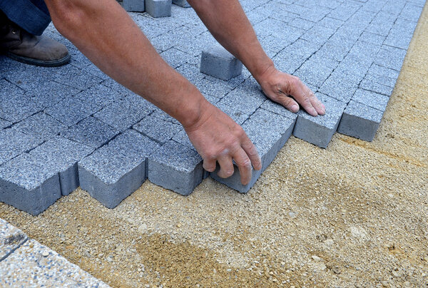 Рабочий сделал тротуар из кирпича
.