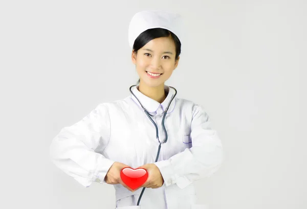 Female nurse with the stethoscope holding heart — Stock Photo, Image