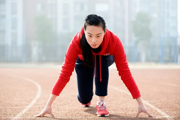 Athletic kinesisk kvinna i startposition på rätt spår — Stockfoto