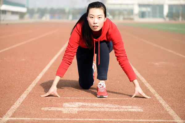 Atletische Chinese vrouw in startpositie op de rails Stockafbeelding