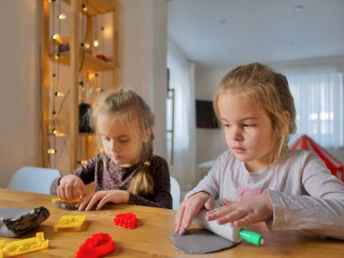 Küçük kızlar kilden bir şeyler yapıyor..