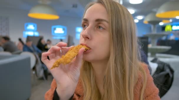 Mujer comiendo pollo por las manos en patio de comida en el centro comercial — Vídeos de Stock