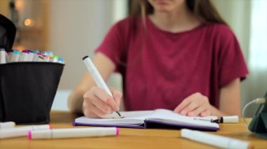 Çizim defterinde işaretleri çizen genç sanatçı kız
