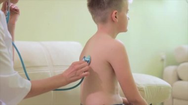 Steteskoplu bir kadın çocuk doktoru, küçük çocuğa teşhis koyuyor.