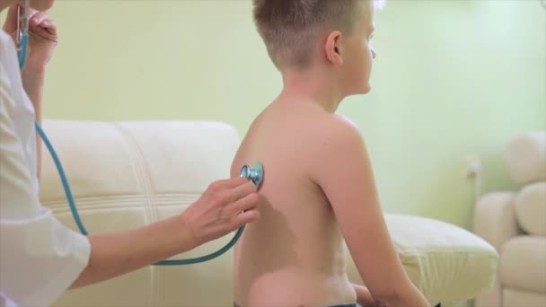 Vrouw kinderarts met stethoscoop diagnosticeren kleine jongen — Stockvideo