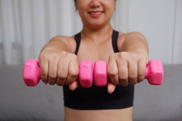 Young Asian women doing exercise at home using dumbbell exercise arms and upper body.