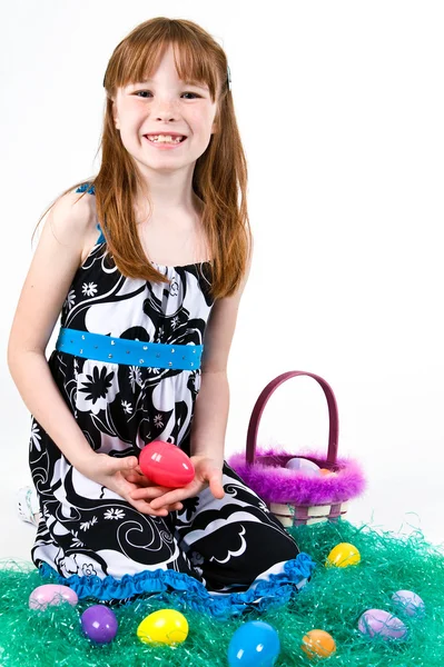 年轻的女孩坐在草与复活节的篮子里，举行复活节彩蛋 — 图库照片