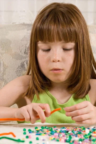 Young girl making bead bracelets — Stock Photo, Image