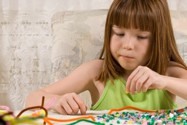Молода дівчина робить браслети з бісеру — стокове фото