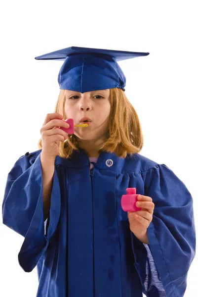 A young graduate in her cap and gown blowing bubbles — Stock Photo, Image