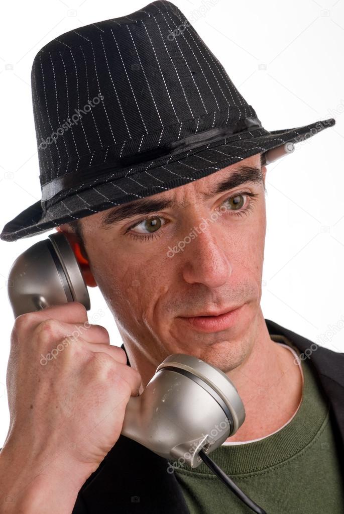 Headshot of Caucasian male wearing a fedora style hat and talking on the phone