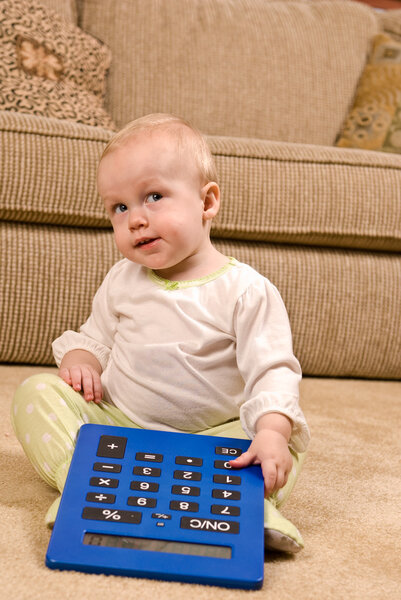 Young baby in pajamas with a large calculator