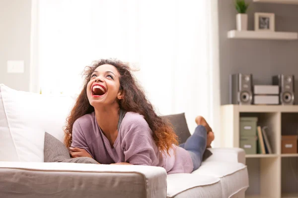 Beautiful afro-american woman happily relaxing lying on a sofa — Stock Photo, Image