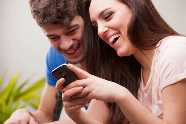 Hombre y mujer se divierten con sus teléfonos móviles — Foto de Stock