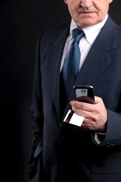 Старый бизнесмен с кредитной картой и мобильным телефоном — стоковое фото