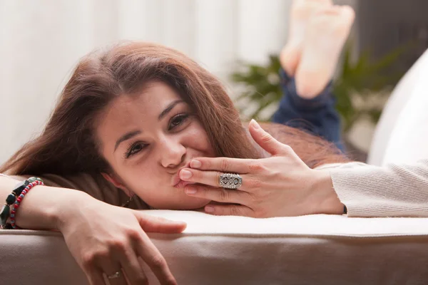 Girl softly sending a little kiss on a sofa — Stock Photo, Image