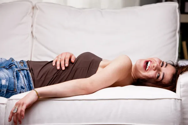 Meisje lachen op haar bank — Stockfoto