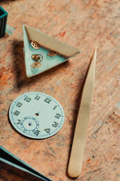 手表的刻度盘或表面上有选择的焦点 用黄铜齿轮和镊子显示在钟表匠工作台上 用于精确工作 — 图库照片