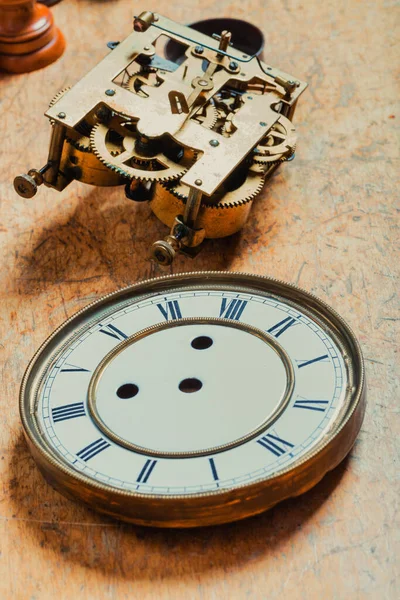 Clock dial and mechanism on a clockmakers workbench in a horology concept in vertical format