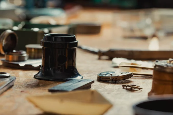 用老式工具和拆卸的钟表机构在钟表匠工作台上选择性地聚焦于珠宝放大镜或放大镜 — 图库照片