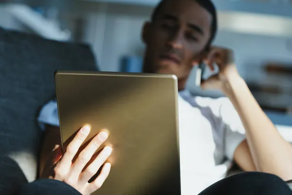 彼の手と太陽光の軸にタブレットに焦点を当て 彼のデジタルノートパッド上の読書や視聴メディアに座っている男 — ストック写真